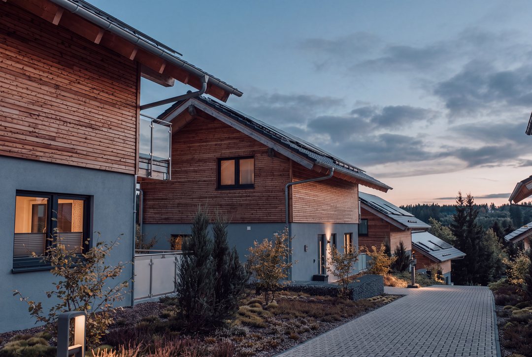 Terraced chalets with warmly lit windows at twilight, designed visual