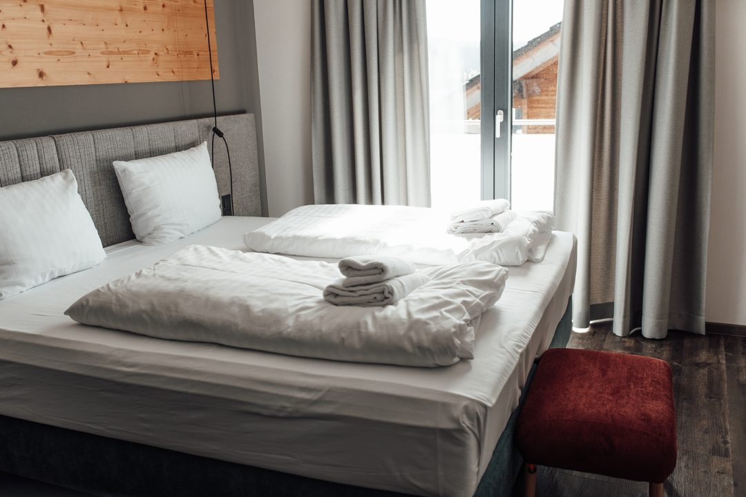 Dormitorio de un chalet con cama de matrimonio, ropa de cama clara y ventana