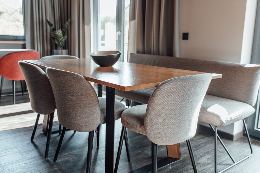 Comedor de un chalet con mesa de madera, sillas y una puerta de terraza de color claro