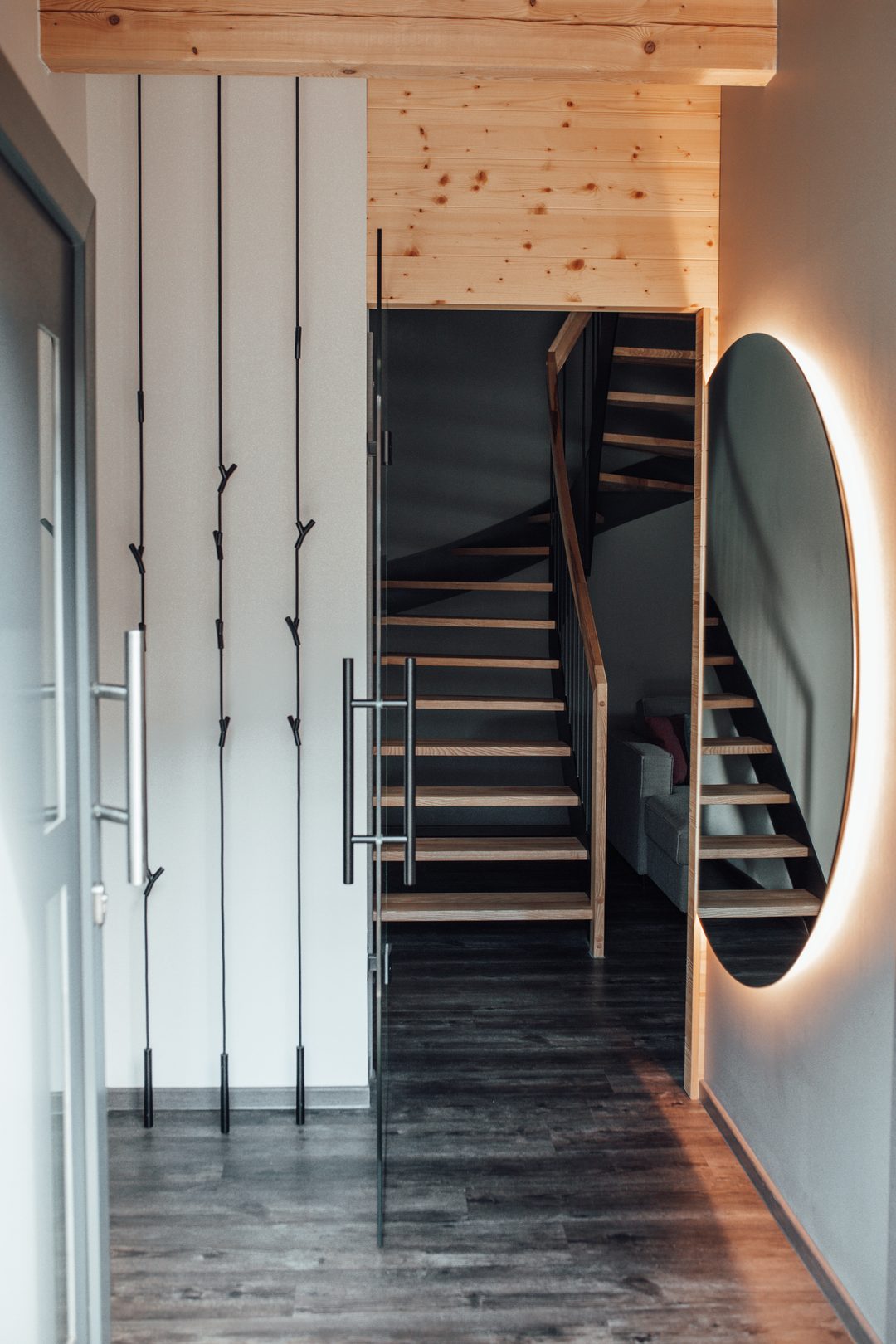 Formato vertical: zona de entrada de un chalet con guardarropa, espejo redondo y escalera