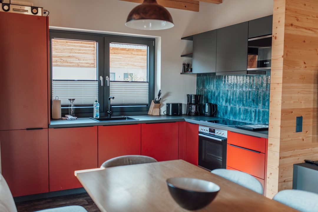 Cocina de un chalet con frentes rojos, encimera de madera y mesa de comedor de madera