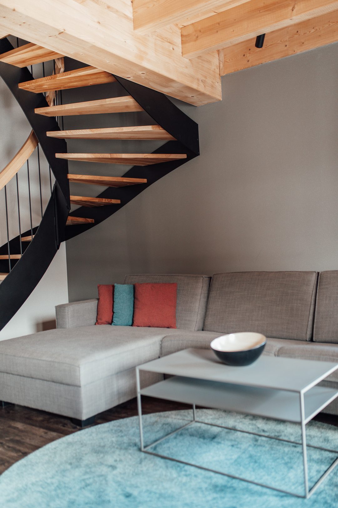 Formato vertical: salón de un chalet con sofá, mesa de centro y escalera