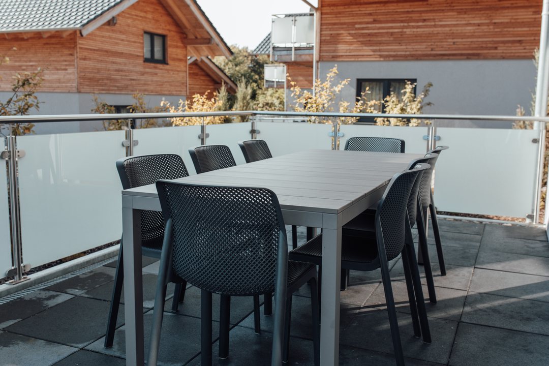 Terraza de un chalet con mesa y sillas; se ven otros chalets al fondo