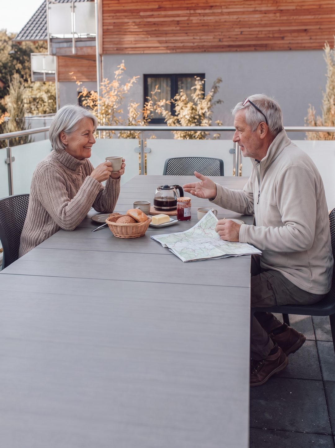 Hochformat: älteres Paar frühstückt auf der Terrasse eines Chalets, Symbolbild